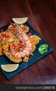King prawn Paella Spanish seafood Paella rice with red and green pepper chili on black stone plate on wood table
