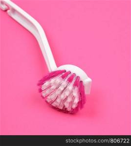 kitchen brush with white plastic handle on a pink background, close up