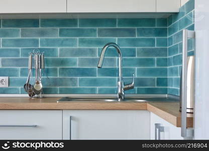 Kitchen Modern white furniture on the wall background with blue tiles. Modern white kitchen furniture