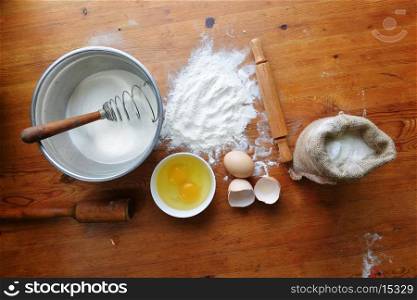 Kitchen rolling pin, eggs and flour on wooden background