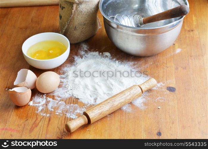 Kitchen rolling pin, eggs and flour on wooden backgroundKitchen rolling pin and flour on wooden background