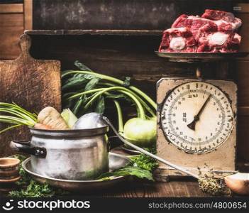 Kitchen table with cooking pot, ladle, vegetables and old weigher with raw meat , preparation of soup , broth or stew, front view. Country style