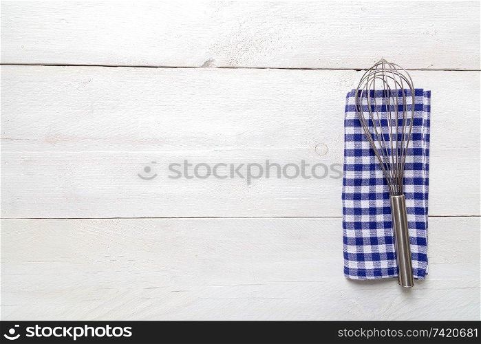 Kitchen towel and whisk on light wood background.. Kitchen towel and whisk on light wood background