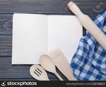 Kitchen utensil and notepad over wooden table background