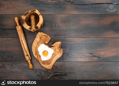 Kitchen utensils and dough ingredients. Rolling pin, mortar and wooden board on rustic background
