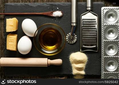 Kitchen utensils and ingredients for homemade pasta ravioli on slate