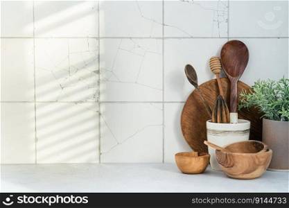 Kitchen utensils background with a blank space for a text and white tile background, home kitchen decor concept with kitchen tools, front view, natural light. Kitchen utensils background