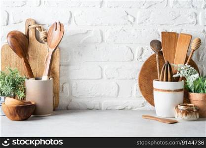 Kitchen utensils background with a blank space for a text and white brick background, home kitchen decor concept with kitchen tools, front view. Kitchen utensils background