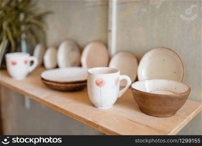 Kitchen utensils on shelf in pottery workshop, nobody. Handmade clay tableware molding and shaping. Kitchen utensils on shelf in pottery workshop