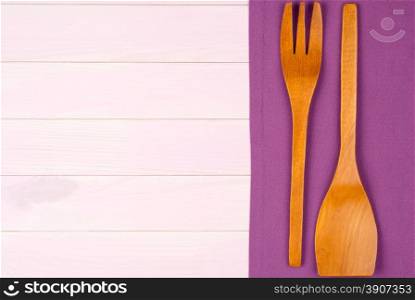 Kitchenware on purple towel over wooden kitchen table. View from above.