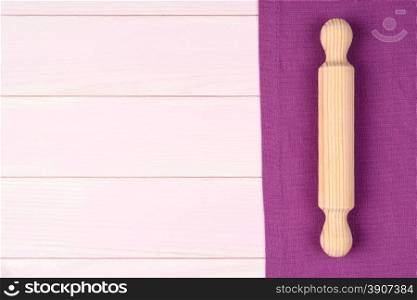 Kitchenware on purple towel over wooden kitchen table. View from above.