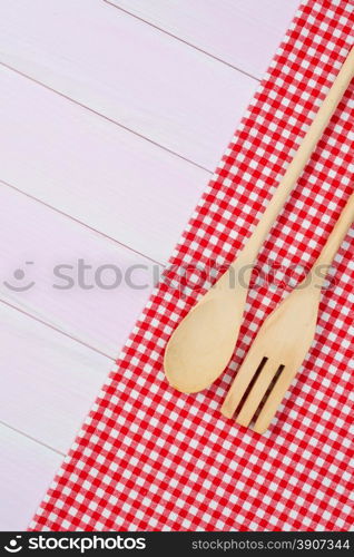Kitchenware on white and red towel over wooden kitchen table. View from above.