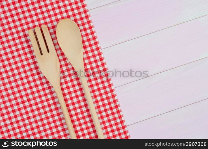 Kitchenware on white and red towel over wooden kitchen table. View from above.