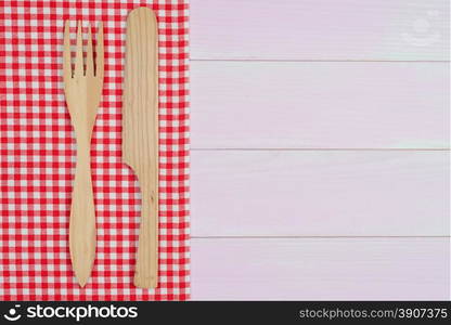 Kitchenware on white and red towel over wooden kitchen table. View from above.