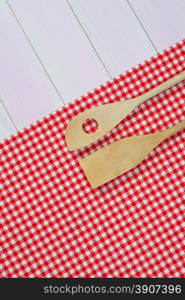 Kitchenware on white and red towel over wooden kitchen table. View from above.