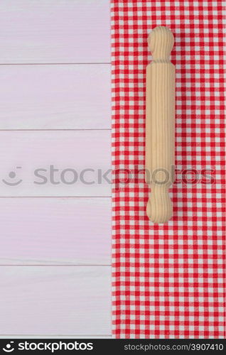 Kitchenware on white and red towel over wooden kitchen table. View from above.