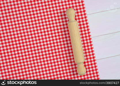 Kitchenware on white and red towel over wooden kitchen table. View from above.