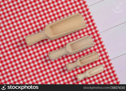 Kitchenware on white and red towel over wooden kitchen table. View from above.