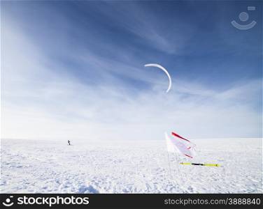 Kite boarder in snowy countryside field with cloudscape background, winter scene