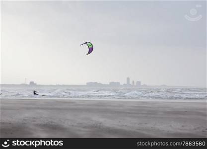 kite surfer and silhouette of zandvoort behind windy beach