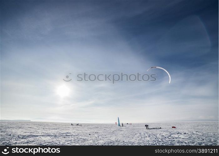 Kite surfer being pulled by his kite across the snow. Kiteboarder with blue kite on the snow