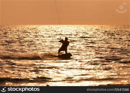 Kite surfer sailing in the sunset sea&#xA;