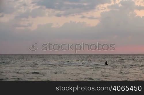 Kite surfer sailing on the sea at sunset