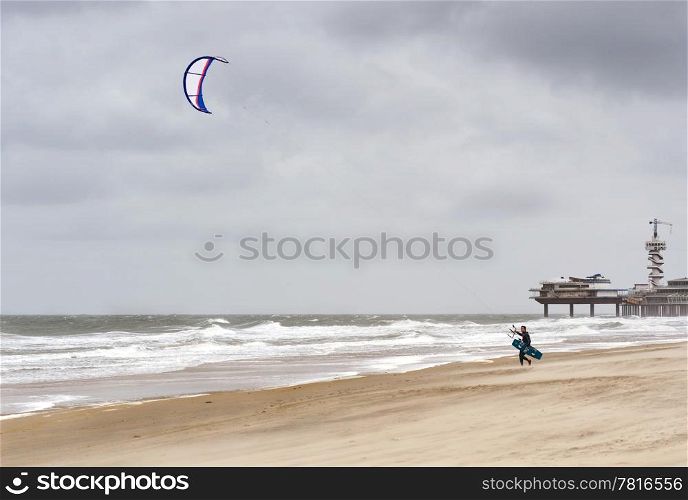 Kite surfer, walking towards the sea on a stormy day at the beach.