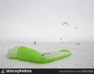 Kiteboarder with blue kite on the snow. Kite surfer being pulled by his kite across the snow