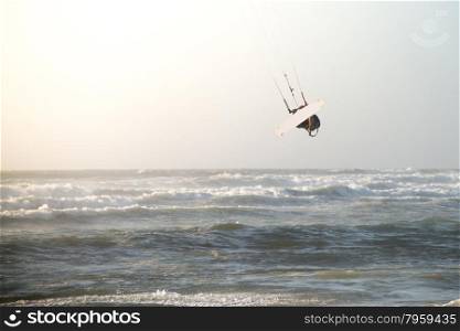 Kitesurfer jumping on a beautiful background of spray during the sunset.