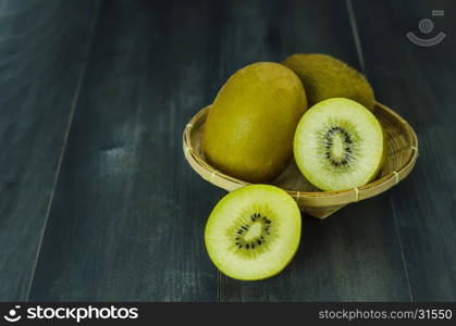 kiwi fruit and sliced with bamboo basket on wooden background , still life