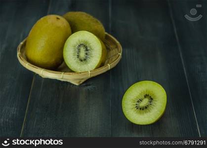 kiwi fruit and sliced with bamboo basket on wooden background , still life