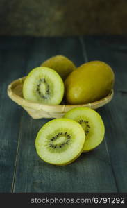 kiwi fruit and sliced with bamboo basket on wooden background , still life