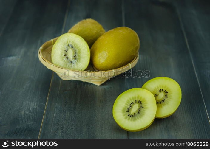 kiwi fruit and sliced with bamboo basket on wooden background , still life