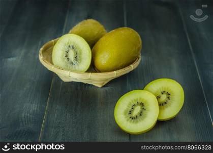 kiwi fruit and sliced with bamboo basket on wooden background , still life