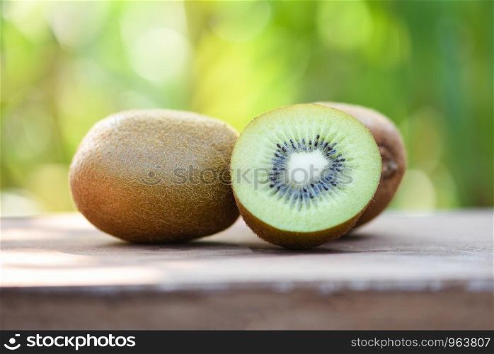 kiwi slices close up and fresh whole kiwi fruit on wooden and nature green background