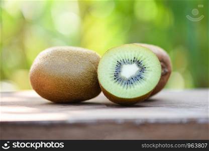 kiwi slices close up and fresh whole kiwi fruit on wooden and nature green background