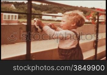 Kleinkind steht an einem Zaun