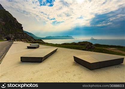 Kleivodden rest stop area viewpoint with stone seating bench. Arctic ocean view with clouds sky. Attractions along Andoya island Vesteralen Norway.. Kleivodden rest area, Andoya Norway