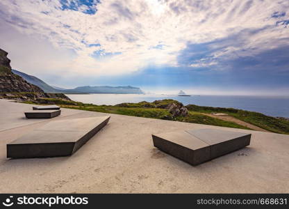 Kleivodden rest stop area viewpoint with stone seating bench. Arctic ocean view with clouds sky. Attractions along Andoya island Vesteralen Norway.. Kleivodden rest area, Andoya Norway