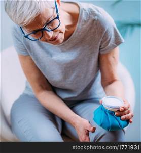 Knee pain treatment. Senior woman holding an ice bag pack on her painful knee . Knee Pain Treatment. Senior Woman Holding Ice Bag Pack on her Painful Knee