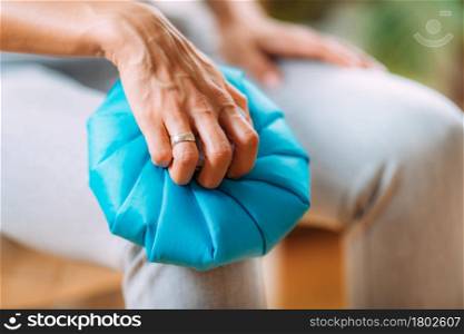 Knee pain treatment. Woman holding an ice bag pack on her painful knee . Knee Pain Cold Compress Ice Bag Treatment.