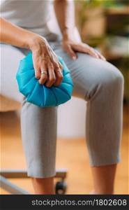 Knee pain treatment. Woman holding an ice bag pack on her painful knee . Knee Pain Cold Compress Ice Bag Treatment.