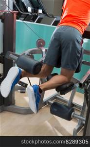 Kneeling leg femoral curl man exercise at gym rear view workout