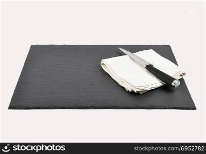 Knife and cloth napkin on slate isolated