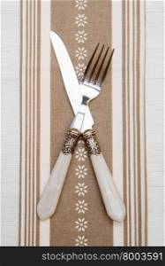 knife and fork at napkin on white wooden background