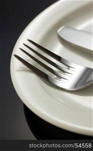 knife and fork at plate on black background