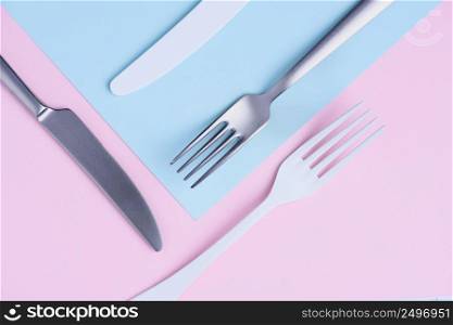 Knife and fork creative flat lay on soft pink and blue trendy pastel background