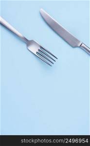 Knife and fork flat lay on soft blue trendy pastel paper background