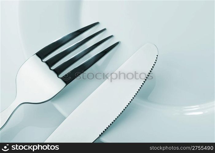 Knife and fork on a plate. Kitchen accessories close up